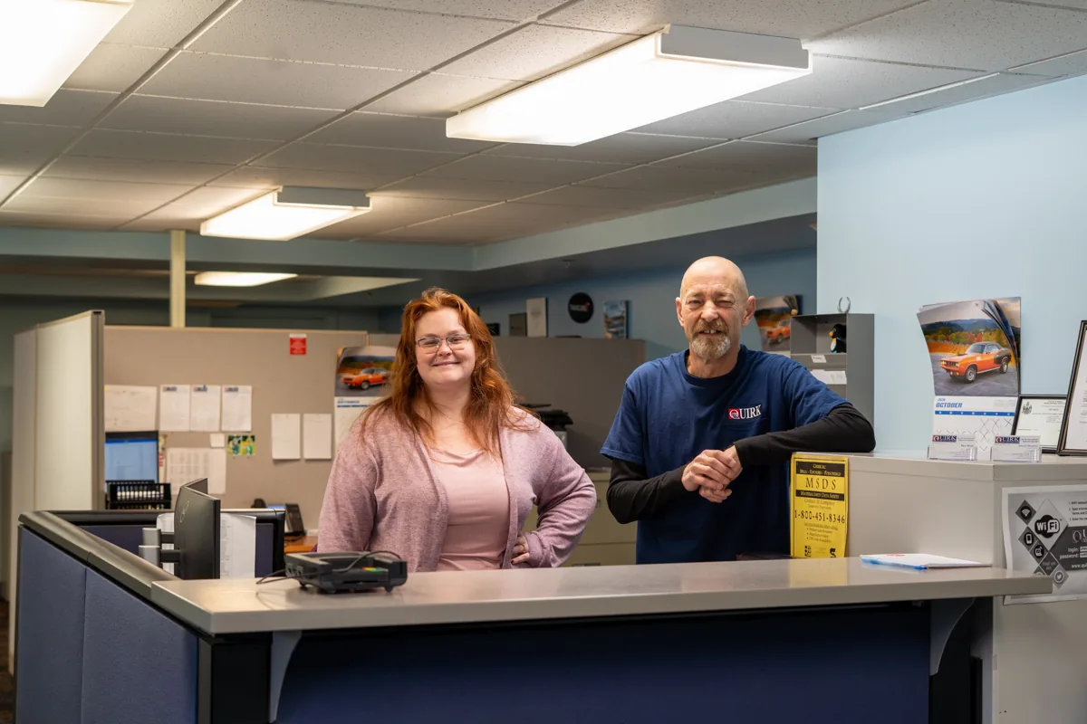 Two Quirk Auto Glass staff members smiling at the front desk