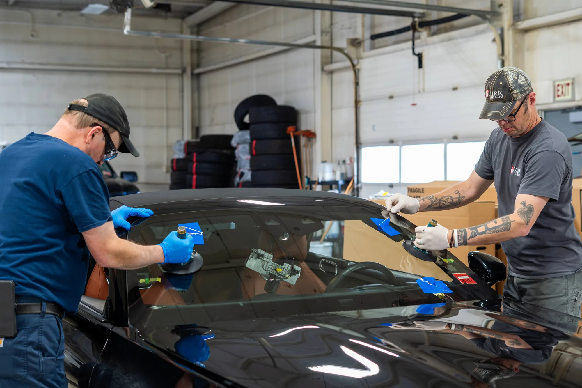 Quirk Auto Glass technicians installing a new windshield on a black Mercedes